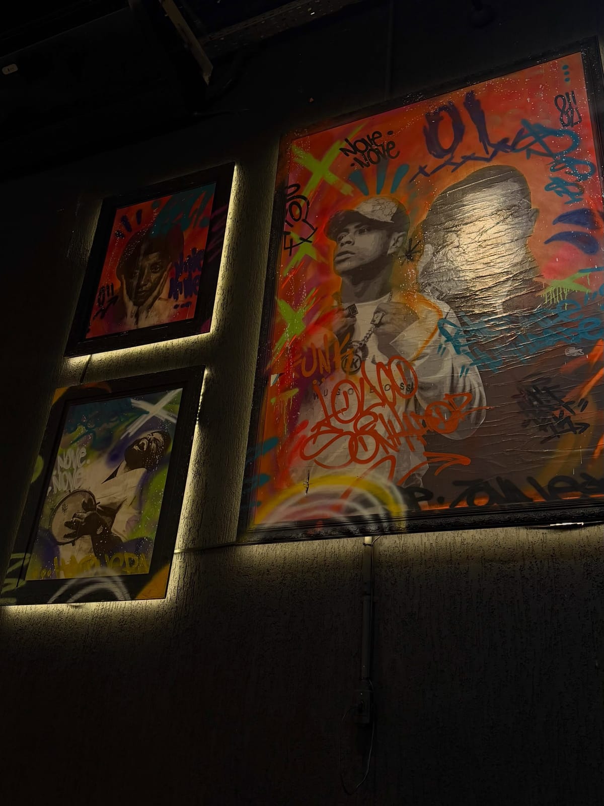 Parede de arte do MD Lounge com quadros emoldurados e luz embutida
